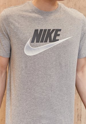 Graues Kurzarm-T-Shirt aus Baumwolle, mit einem schwarzen "NIKE"-Logo und einem weißen Swoosh-Design über der Brust.