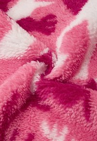 Coperta in pile rosa e bianca, con una morbida texture pelosa e un motivo a gradiente di diverse tonalità di rosa.