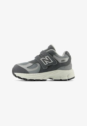 Gray athletic shoe with suede and mesh materials, double velcro strap, rubber sole, and reinforced toe; features "N" logo on the side.