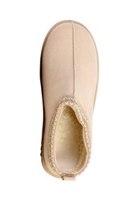 Mule en daim beige avec couture visible autour de l'ouverture et doublure intérieure douce et pelucheuse, vue de dessus.