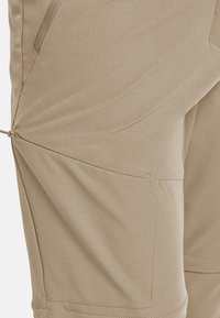 Shorts beige longueur genou en tissu léger, avec une poche zippée latérale et un détail élastique froncé à l'ourlet pour plus de réglabilité.