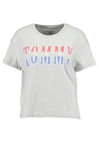 Camiseta de algodón gris con cuello redondo, que presenta un atrevido texto "TOMMY" en rojo y azul en la parte delantera. Con mangas cortas y corte relajado.