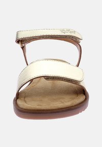 Sandales dorées à lanières légères avec une semelle intérieure en suède marron doux, dotées de deux brides de cheville réglables et d'une semelle en caoutchouc plate.