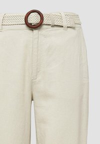 Geweven beige riem met een ronde houten gesp, gecombineerd met beige linnen broek, die een soepele textuur en rechte snit toont.