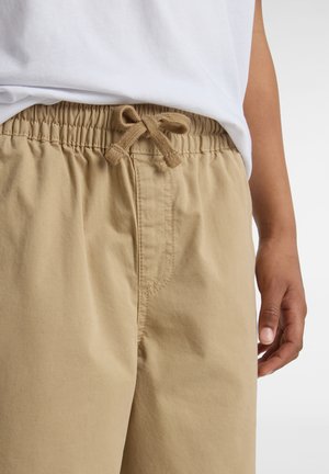 Pantalones cortos caqui con cintura elástica y cordón, que presentan una textura suave y detalles cosidos en la zona de los bolsillos frontales.