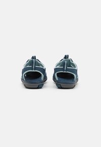 Blue sandals with a breathable fabric upper and open heel design. Features a rubber sole and pull tabs on the heel for easy wear.