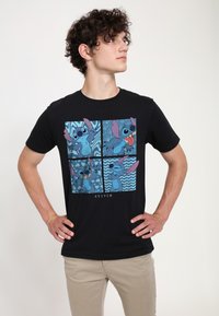 Czarny T-shirt z kolorową grafiką przedstawiającą Stitcha w czterech panelach, ukazującymi różne wyrazy twarzy i wzory w odcieniach niebieskiego na czarnym tle.