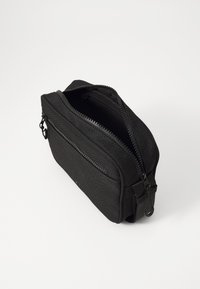Black fabric pouch with a textured surface, featuring two zippered compartments and a side loop for attachment. Compact rectangular design.