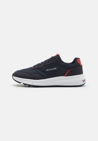 Marine sneakers med hvit såle, som har røde detaljer. Stoffoverdel med forsterket hæl, snøring og merkevaredetaljer på siden.