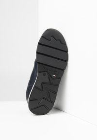 Baskets navy avec une semelle en caoutchouc texturée arborant un motif en zigzag, accentuées d'une bande blanche et d'un logo sur le talon.