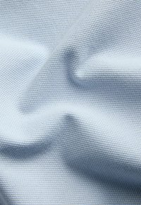 Tissu bleu clair texturé avec un petit motif gaufré et de douces plis créant des ombres et des lumières.
