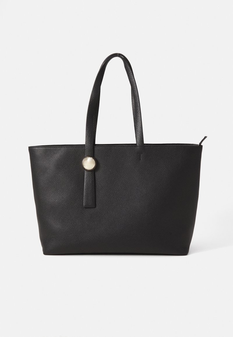 Sac fourre-tout en cuir noir avec surface texturée, deux longues poignées et un accent en bouton argenté circulaire sur une sangle verticale.