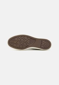 Suola di scarpa da ginnastica in gomma marrone con pattern testurizzato e bordo crema. Presenta un design esagonale e il logo del marchio. Superficie liscia con accenti di presa.