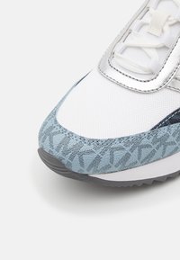 Men's sneaker featuring a white mesh upper, light blue textured accents, silver detailing, and a patterned rubber sole.