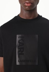 Fekete pamut póló, középen, tonális fekete nyomtatott logóval: "KARL LAGERFELD". Klasszikus kerek nyakú dizájn.