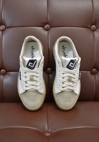 Sneaker bianche e beige realizzate in suede e pelle; punta rotonda; numerose perforazioni; lacci piatti; suola in gomma; logo sul lato.