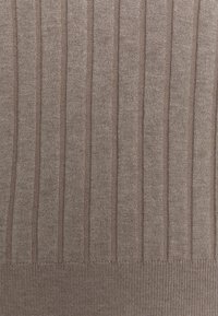 Brązowy sweter z dzianiny o pionowej prążkowanej fakturze i kontrastem między jasnymi a ciemnymi nitkami, z dopasowanym, prążkowanym mankietem.