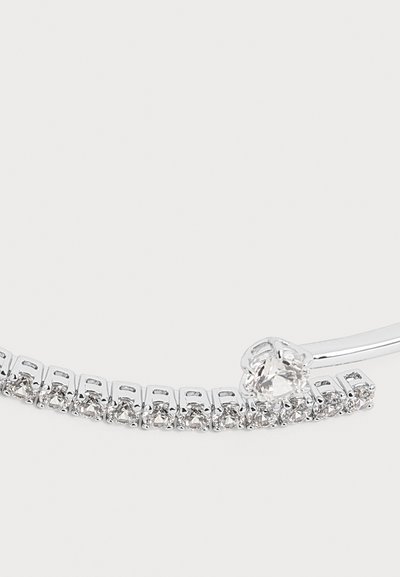 Bracelet en argent avec une rangée de petites pierres précieuses transparentes et une plus grande pierre précieuse ronde comme fermoir sur fond blanc.