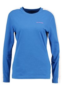 Långärmad blå bomullströja med vita sidostripes och texten "Calvin Klein Jeans" i ljusrosa, rund halsringning och normal passform.