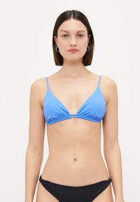 Top bikini blu ribbed con coppe triangolari e spalline sottili regolabili, caratterizzato da un dettaglio centrale a nodo. Abbinato a un bikini bottom nero.