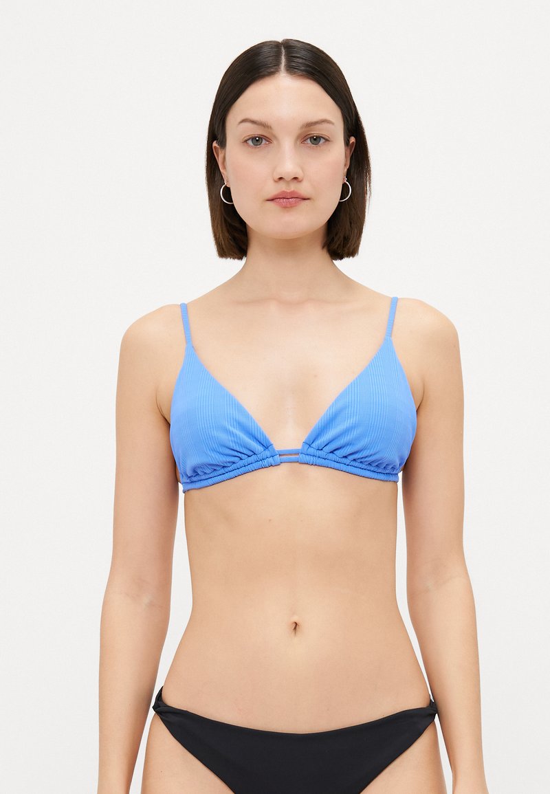 Top bikini blu ribbed con coppe triangolari e spalline sottili regolabili, caratterizzato da un dettaglio centrale a nodo. Abbinato a un bikini bottom nero.