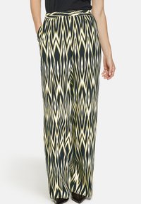 Wide-leg pants in a black, yellow, and white zigzag pattern. Made of lightweight fabric with a smooth texture and side pockets.