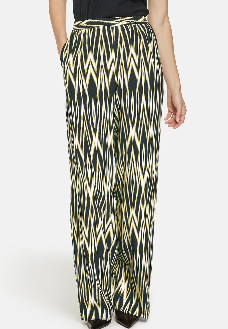 Wide-leg pants in a black, yellow, and white zigzag pattern. Made of lightweight fabric with a smooth texture and side pockets.