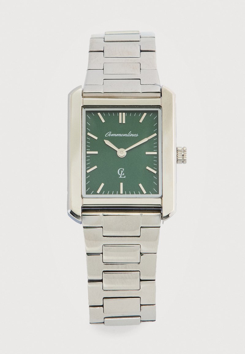 Ορθογώνιο ασημένιο μεταλλικό ρολόι χειρός με πράσινο καντράν, ασημένιους δείκτες ώρας, δείκτες που δείχνουν 9:12 και το όνομα της μάρκας «Commonlines» στο καντράν.