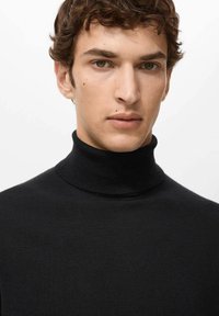 Zwarte gebreide coltrui met een nauwsluitende pasvorm en geribbelde textuur, uitgevoerd met lange mouwen en een hooggesloten hals.