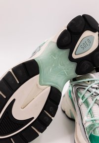 Scarpe sportive con suola in gomma nera, intersuola traslucida verde menta e parte superiore in mesh bianco con accenti grigi e verdi menta.