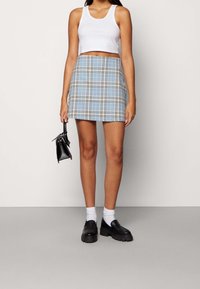 Blårutig mini kjol i lätt tyg, med vita och svarta linjer, kombinerad med en vit crop top och svarta plattformskor.