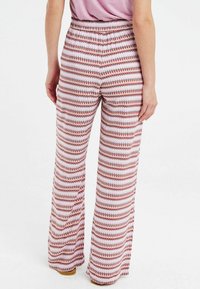 Geprinte wijde pijpen broek met een rekbare tailleband, voorzien van een zigzagpatroon in rode, witte en paarse tinten, en een zachte stof textuur.