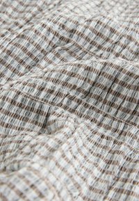 Kootud kangas, millel on vahelduvad kitsad triibud pruunis, kreemjas ja hallides toonides, krimpsutatud pinnaga ja pehme langev.