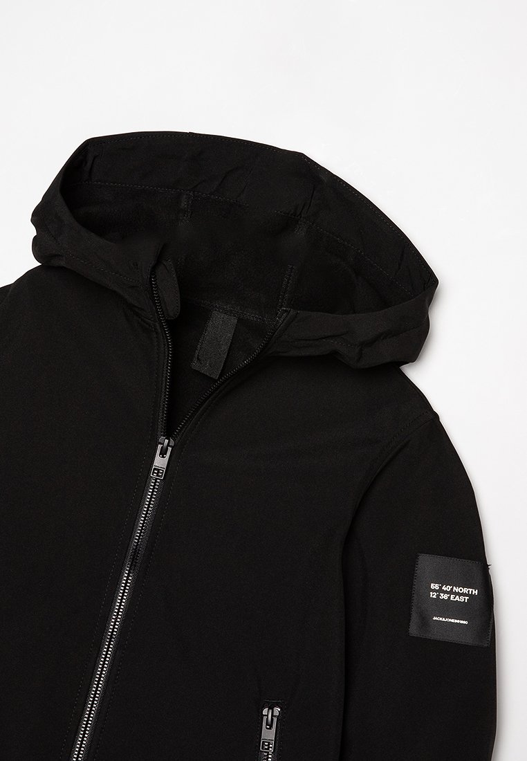 Chaqueta negra con capucha hecha de tela suave. Presenta un cierre de cremallera completo, dos bolsillos laterales y una parche en la manga izquierda con coordenadas.