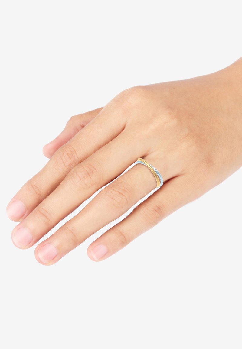 Metalring med sammenflettede bånd i guld og lyseblå, med glatte overflader og et slankt design, båret på en hånd.