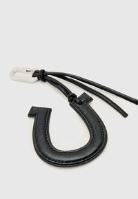 Svart lädernyckelring formad som en hästsko, med kontrastsömmar och ett tunt läderband med en silverfärgad metallfäste.