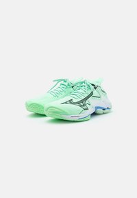 Scarpe da corsa verde chiaro con tomaia in rete traspirante, dettagli neri, suola texturizzata e supporto imbottito, caratterizzate da una finitura liscia.