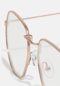 Ochelari de soare aviator din metal, cu ramă roz aurie, lentile transparente și accente texturate pe bara sprâncenei. Include pernuțe pentru nas ajustabile.