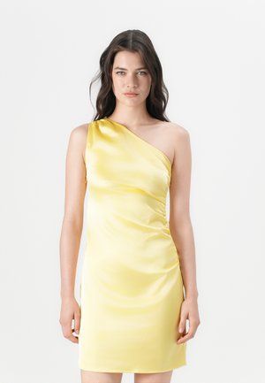 Robe jaune satin à une épaule avec une silhouette ajustée, détail drapé sur le côté et texture lisse. Courte, atteignant au-dessus du genou.