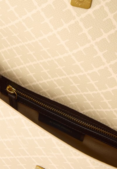 Εσωτερικό μπεζ τσάντας με σχέδιο, με τσέπη με χρυσό φερμουάρ και σκούρο καφέ περιθώριο.