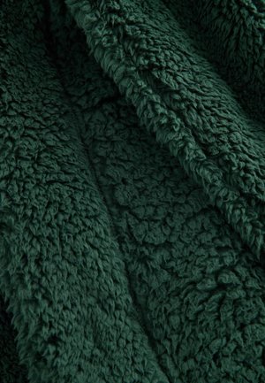 Roheline fliisriie musterdusega, pehme ja koheva pinnaga; omab rikkalikku, sügavat tooni ning pehmet, sooja tunnet, sobides ideaalselt hubasteks kasutusteks.