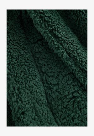 Roheline fliisriie musterdusega, pehme ja koheva pinnaga; omab rikkalikku, sügavat tooni ning pehmet, sooja tunnet, sobides ideaalselt hubasteks kasutusteks.