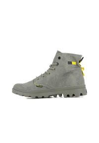 Hoch geschnittene grüne Stiefel mit einer strukturierten Oberfläche, kontrastierenden gelben und schwarzen Akzenten sowie einer robusten Sohle mit ausgeprägtem Profil.