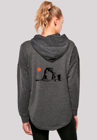 Dunkelgrauer Hoodie mit einem großen schwarzen Grafikdesign eines Bogens und einer Sonne auf dem Rücken. Lange Ärmel mit Kordelzugkapuze und geschwunghem Saum.