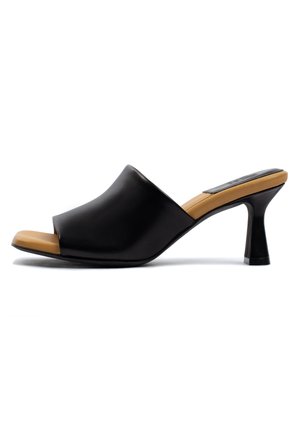 Mule nera open-toe con un'esterno liscio, tacco a blocco basso e soletta di un marrone chiaro a contrasto. Presenta un design curvo e facile da indossare.