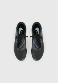  svarte sportsko med teksturert overflate, blå detaljer og Nike-merke. Har snøring og et slankt, moderne design.