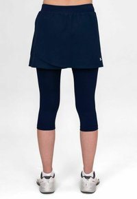 Skort atlético azul marino con un diseño en capas, acompañado de mallas capri azul marino. El material parece ligero y suave. Cintura reforzada.