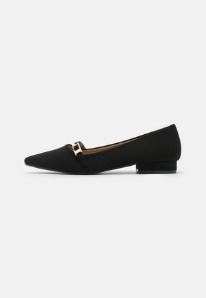 Zwarte platte schoenen met een puntige neus, suède textuur, minimale gespdetails en een lage hak. Eenvoudig en strak ontwerp.