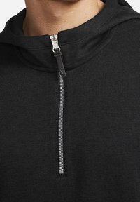 Svart huva sweatshirt med ribbat mönster, med en frontdragkedja och en lätt krage. Dragkedjan är metallisk med svarta detaljer.