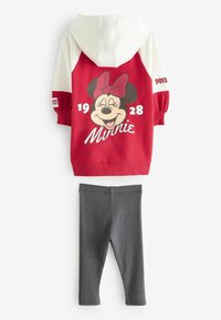 Červená a biela mikina s kapucňou s potlačou postavičky Minnie Mouse, kombinovaná so sivými legínami. Mikina obsahuje predné vrecko a rebrované manžety.